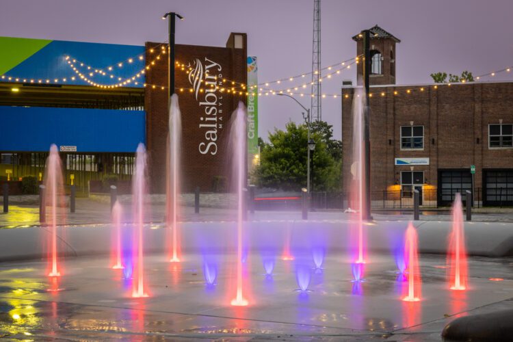 Splashpad in evening with red and purple LED lights.