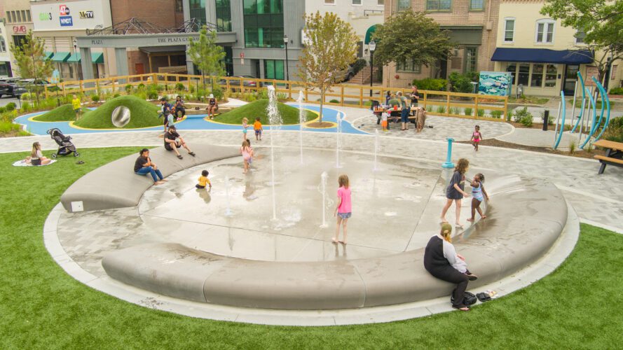 Unity Square splash pad during the day with several kids playing in water.