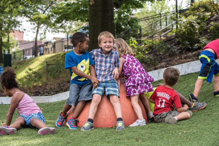 Group of smiling kids sitting on playground equipment.