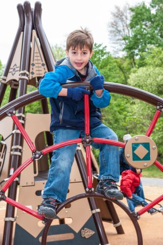 Kid playing on circular climbing structure.