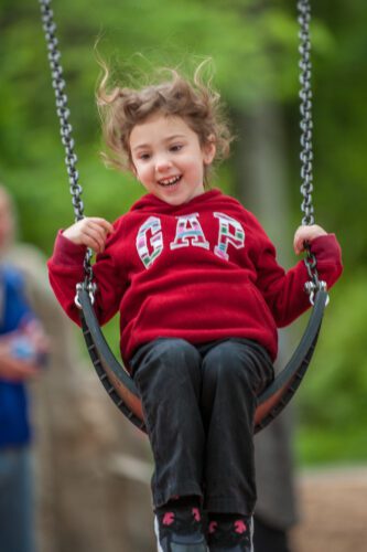 Smiling girl in red sweater on swing.