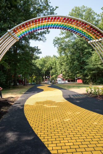 View of yellow brick road going under large rainbow arch.
