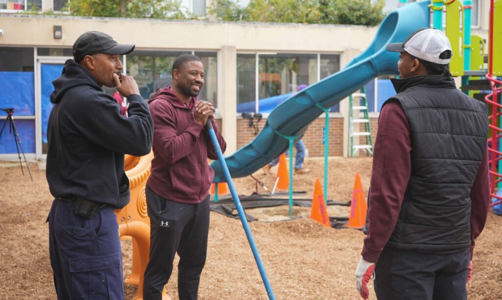 3 guys smiling at playground construction site.