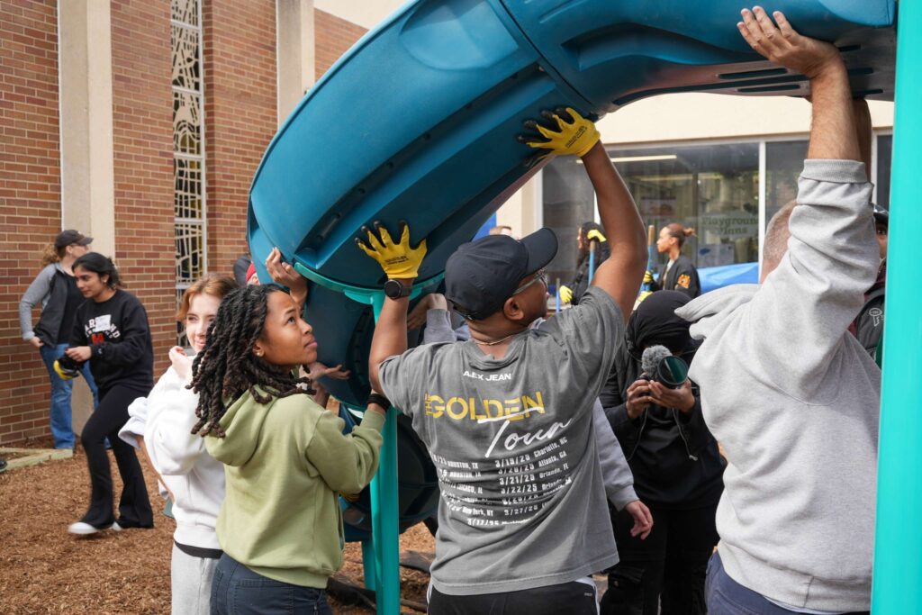 Students helping install slide at playground construction site.