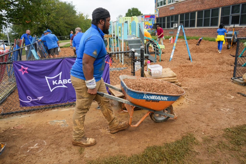 Man with a wheelbarrow of mulch/dirt.