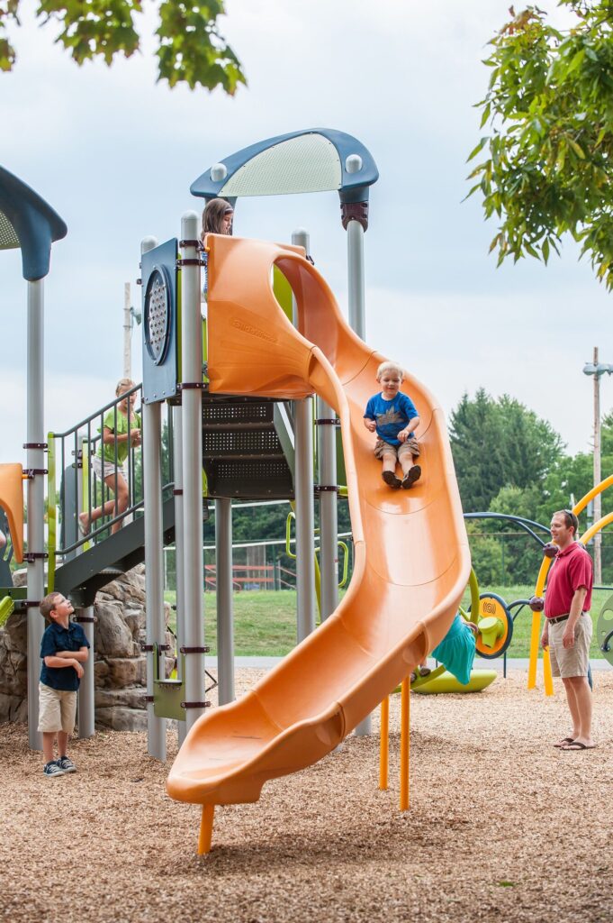 Boy on tall orange slide.