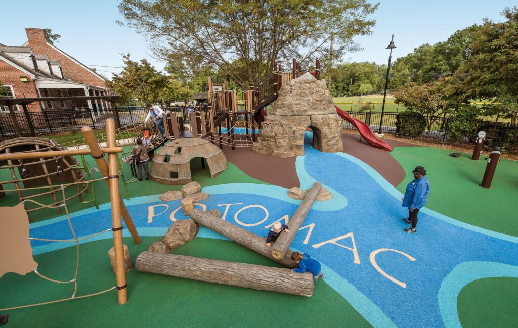 View of a playground with blue surfacing with the word "Potomac" labeling it as a river.