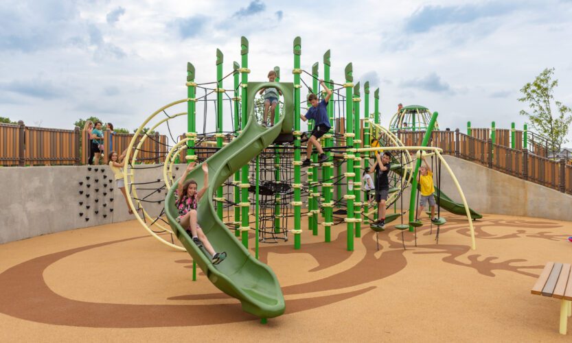 View of large playground equipment with slide in front.