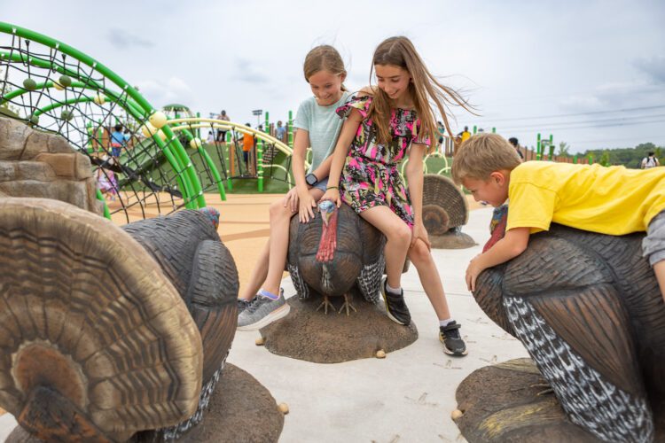 Kids playing on several turkey statues that create a circle.