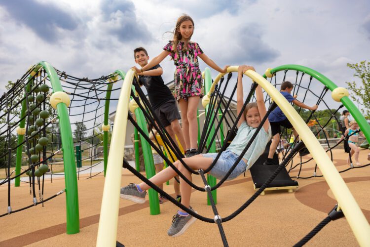 3 kids playig on arched netting playground equipment.