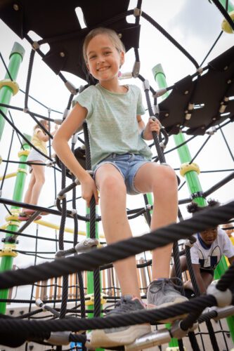 Girl sitting on net playground equipment.