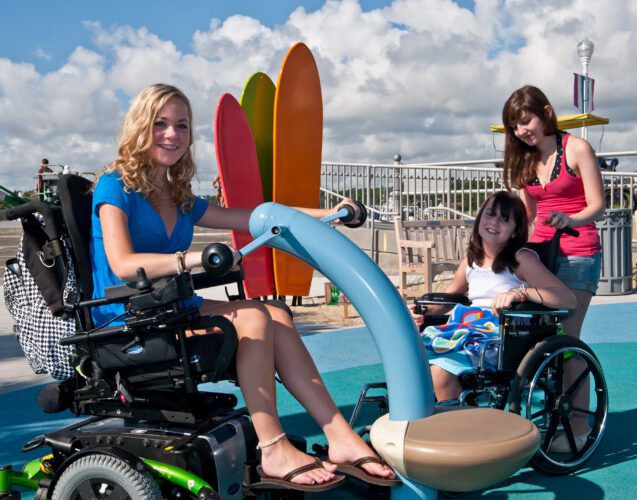 3 girls, 2 in wheelchairs, playing on playground