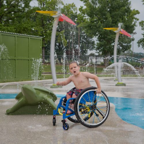 Boy in wheelchair playing at splashpad.