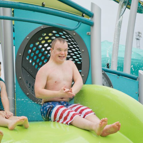 Boy going down green slide.