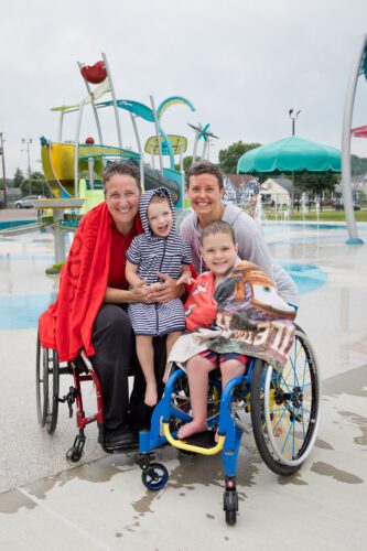 Family smiling with splash pad in background