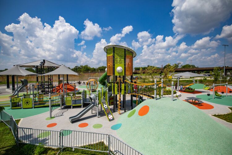 Overview of the Fields at RFK playground in Washington, DC, featuring custom LSI PlayBooster® tower, Netplex® structure, freestanding play components, and vibrant Poured-in-Place surfacing by Surface America, installed by Sparks at Play.