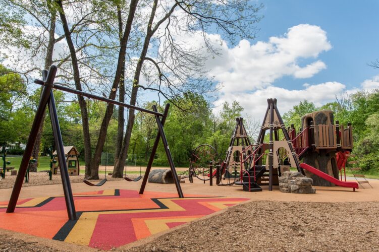 Overview of the Indian Creek Playground in Berwyn Heights, MD, featuring custom teepee play structures, nature play elements, and colorful pour-in-place surfacing, installed by Sparks at Play using LSI equipment.
