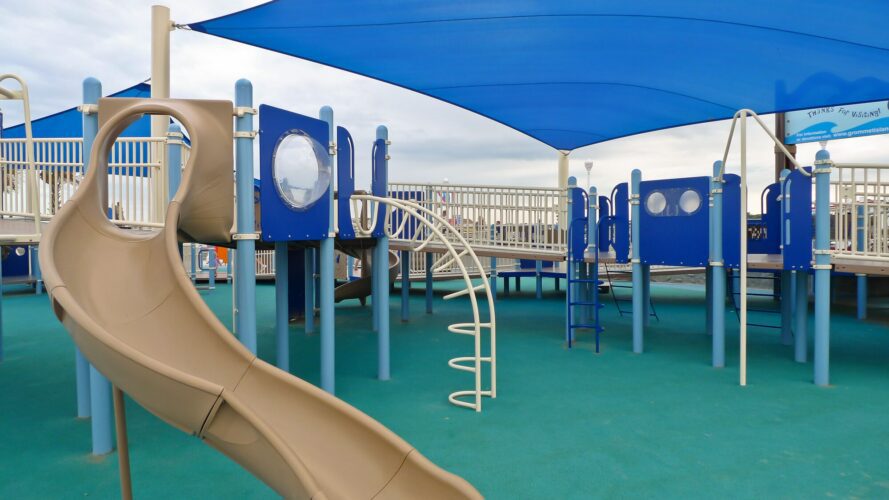 Overview of the play structure and LSI SkyWays® shade structure at JT's Grommet Island Beach Park Playground for EveryBODY in Virginia Beach, VA, installed by Sparks at Play.