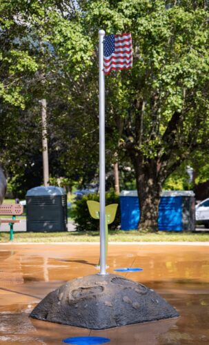Custom American flagpole with Wood Booger footprints at the base at the City of Norton splash pad in Norton, Virginia, installed by Sparks at Play.