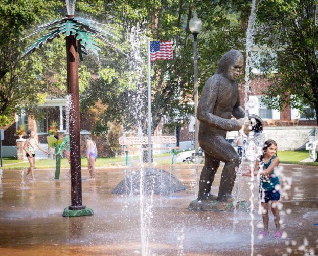 Custom GFRC Norton Wood Booger statue alongside the Pine Tree Shower water feature at the City of Norton splash pad in Norton, Virginia, installed by Sparks at Play using Aquatix equipment.