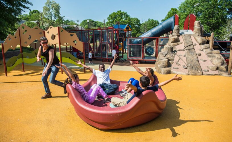 Parent spinning kids on Landscape Structures OmniSpin Spinner at Turkey Thicket Recreation Center playground Washington DC