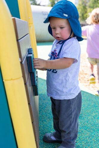A young boy interacting with an LSI learning panel at the Jennie Dean Park playground in Arlington, VA, installed by Sparks at Play.