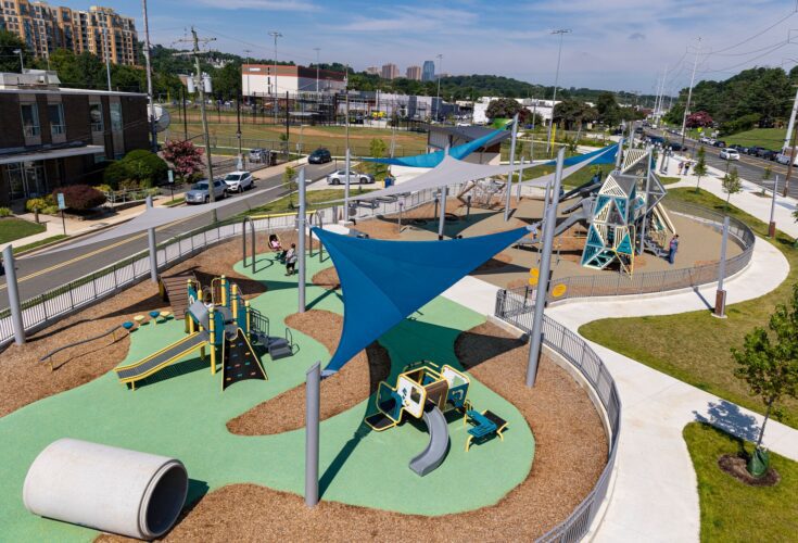 Overview of the Jennie Dean Park playground in Arlington, VA, featuring Alpha Link® Towers, age-specific play zones, hillside slides, and SkyWays® shade structures, installed by Sparks at Play using LSI equipment.