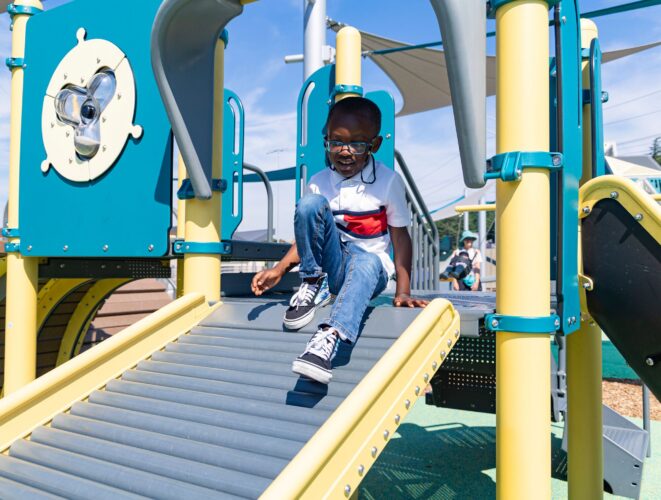A child at the top of the Rollerslide at the Jennie Dean Park playground in Arlington, VA, installed by Sparks at Play using LSI equipment.