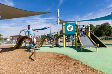 A child navigating the LSI Curved Balance Beam at the Jennie Dean Park playground in Arlington, VA, building balance and coordination, installed by Sparks at Play using LSI equipment.