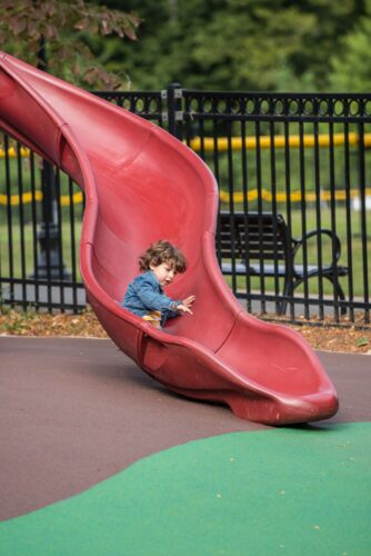 A child going down the slide at the Palisades Recreation Center playground in Washington, DC, installed by Sparks at Play using LSI equipment.
