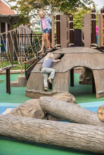 A child climbing up the outside of the custom hut at the Palisades Recreation Center playground in Washington, DC, installed by Sparks at Play using LSI equipment.