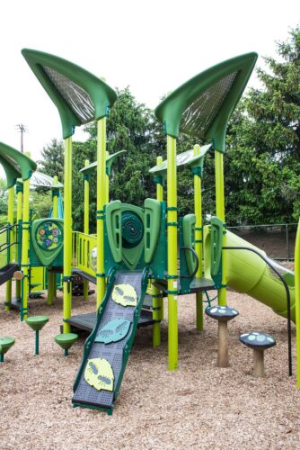 Custom grass-themed play structure with giant blade of grass climbers at the Prince George's County Childcare playground in Upper Marlboro, MD, installed by Sparks at Play using LSI equipment.