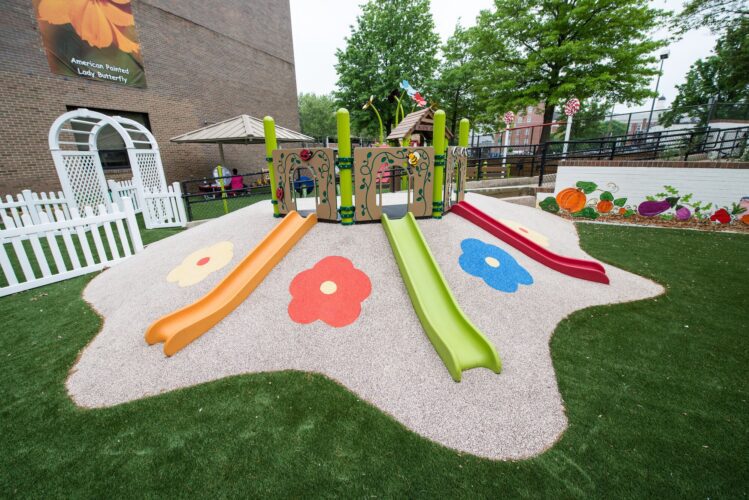 Colorful slides on an elevated hill designed for toddlers and young children at the Prince George's County Childcare playground in Upper Marlboro, MD, installed by Sparks at Play using LSI equipment.