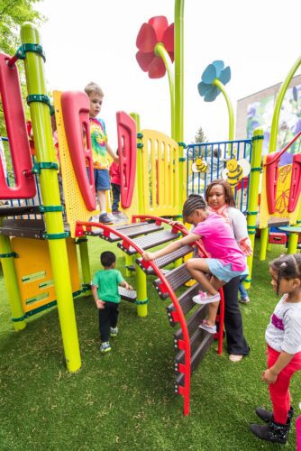 Children climbing up a bridge at the Prince George's County Childcare playground in Upper Marlboro, MD, installed by Sparks at Play using LSI equipment.