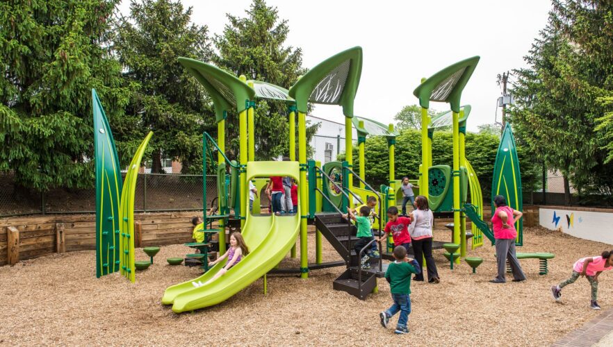 Overview of the custom garden-themed Prince George's County Childcare playground in Upper Marlboro, MD, featuring PlayBooster® structure, custom climbing elements, and colorful surfacing, installed by Sparks at Play using LSI equipment.