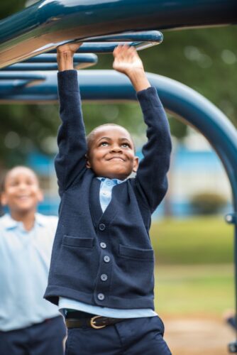 Kid climbing across Landscape Structures Smart Play Venti at Princeton Elementary School playground Suitland MD