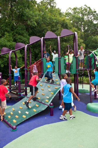 Children climbing the custom dragon wing climbing wall on the medieval-themed play structure at South Bowie Community Center in Bowie, MD.