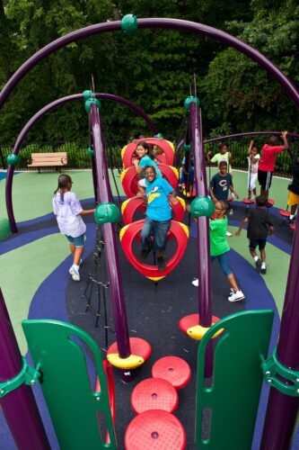 Children climbing through the O-Zone® Climber integrated into the custom medieval dragon play structure at South Bowie Community Center in Bowie, MD.