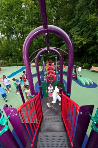 Children climbing through the O-Zone® Climber integrated into the custom medieval dragon play structure at South Bowie Community Center in Bowie, MD.